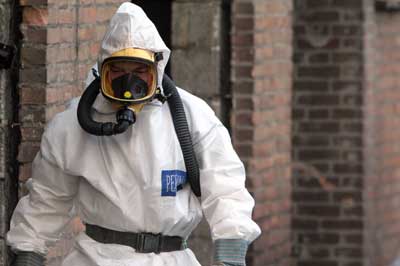 Foto van man in wit pak tijdens verwijderen asbest | Archief EHF
