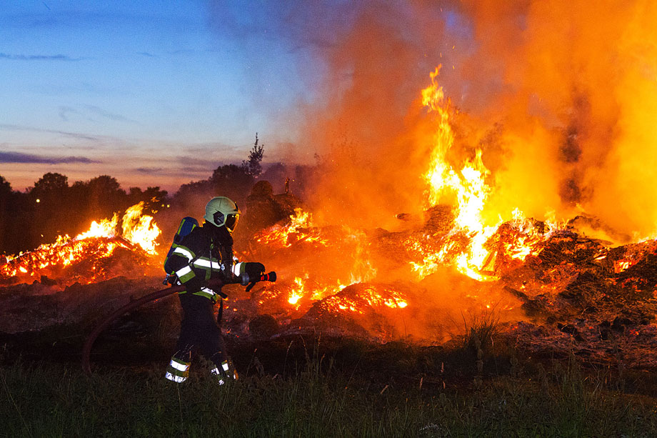 Brandweer druk met blussen stapel afval van boomkwekerij