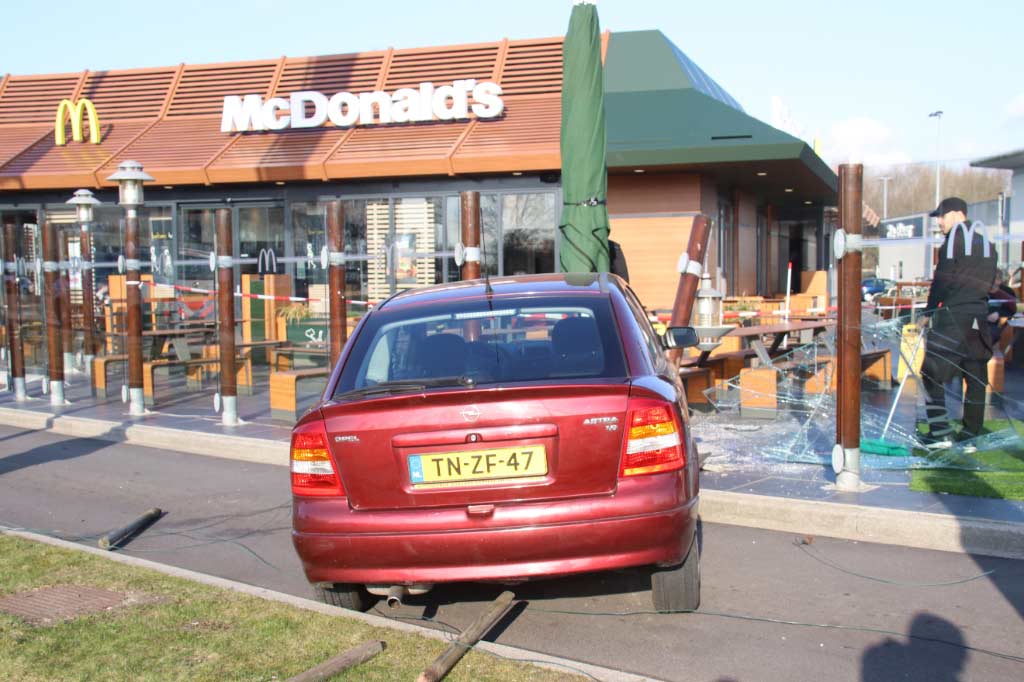 Automobilist rijdt met auto terras McDonald's op