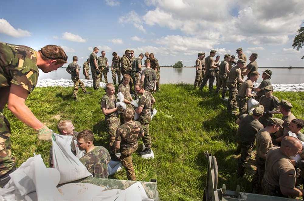 Foto van militairen die dijk verstevigen | Min. Defensie