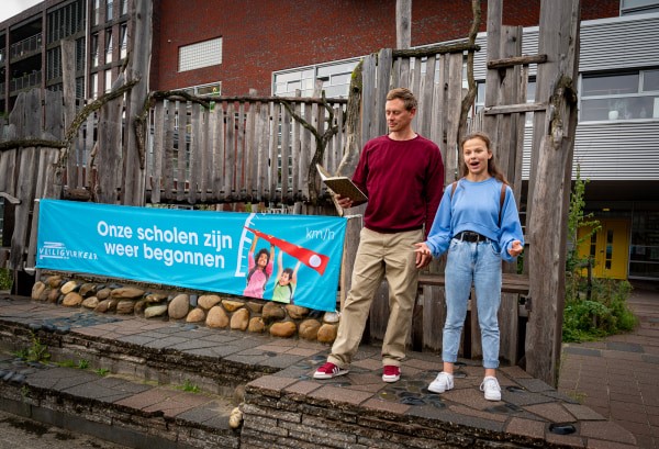 Justin Samgar en scholier Anna dragen het gedicht “Onze scholen zijn weer begonnen” voor bij basisschool de Hasselbraam in Amsterdam.