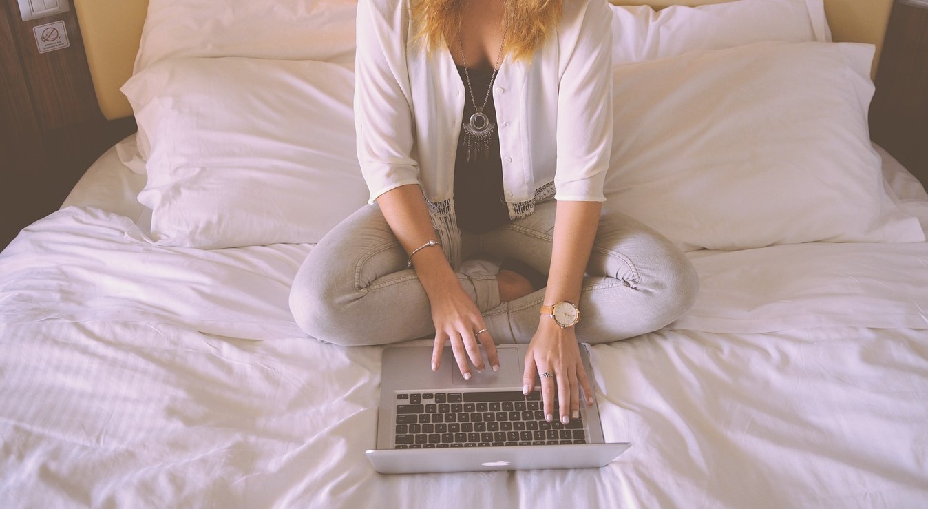 Vrouw op bed achter laptop