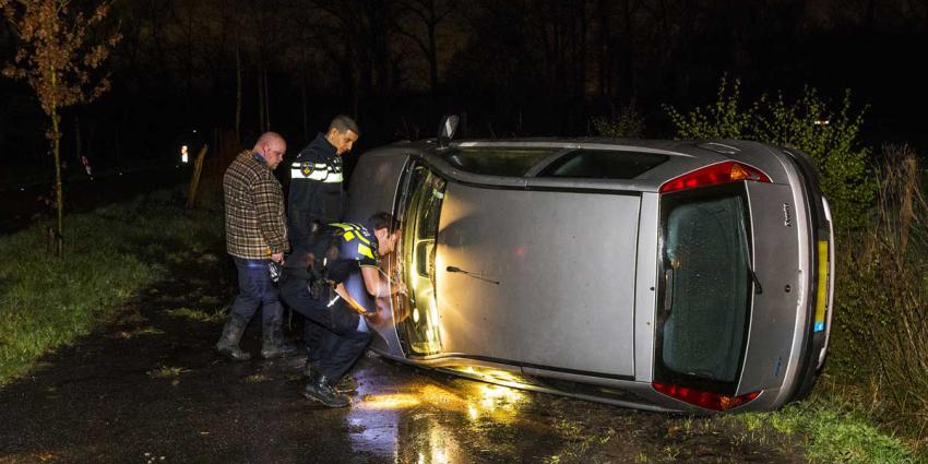 Auto op zijn kant in Oirschot, buurtbewoner schiet te hulp
