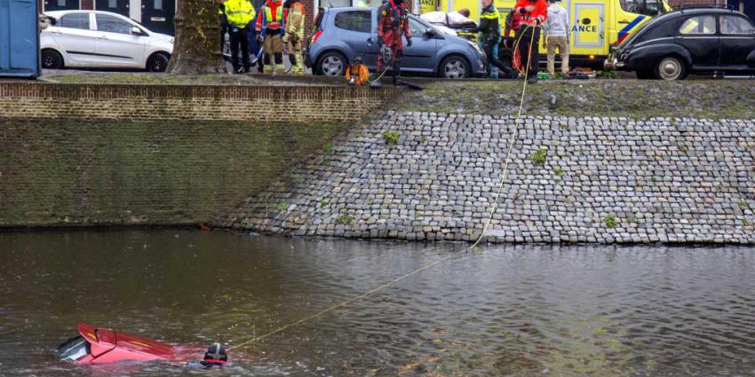Omstanders halen man uit te water geraakte auto Schiedam