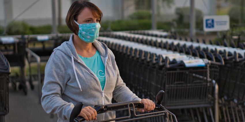 Vrouw met mondkapje en winkelwagen