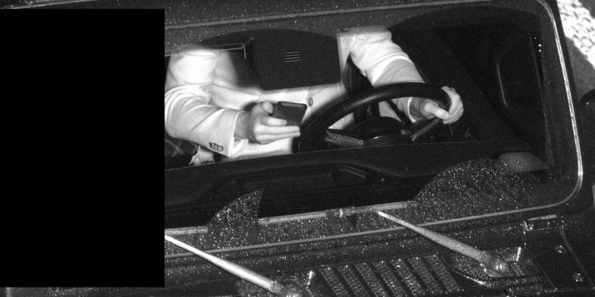 Bestuurder met mobiel in de hand