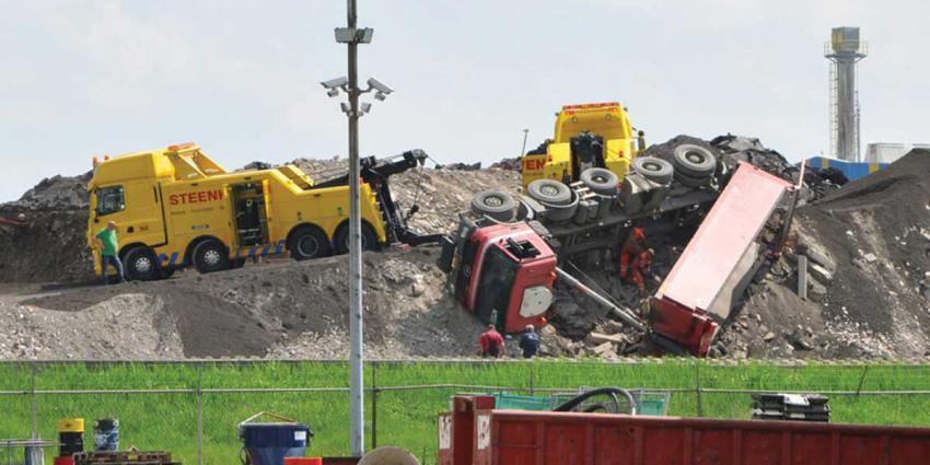 Vrachtwagen valt van puinberg bij afvalverwerker