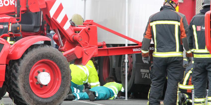 Persoon bekneld onder vrachtwagen 