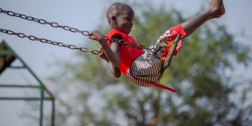 Een meisje schommelt buiten bij de kindvriendelijke ruimte in Palorinya Refugee Settlement in Obongi District, Oeganda