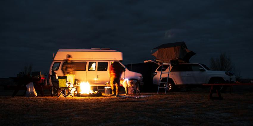 Camper in het donker bij kampvuur