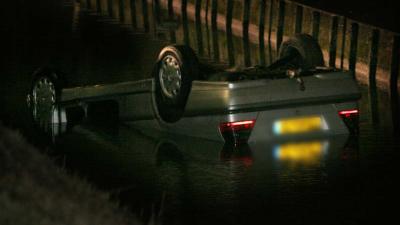 Auto op zijn kop in water, politie en omstanders redden gezin