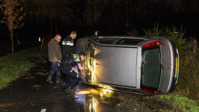 Auto op zijn kant in Oirschot, buurtbewoner schiet te hulp