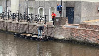 een oude fiets wordt uit het water gehaald