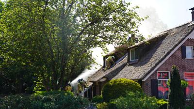 Brandweermannen halen rieten dak uit