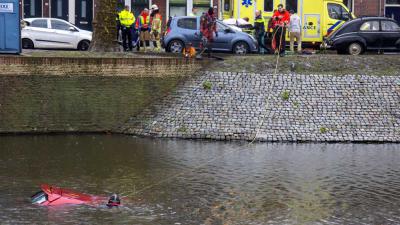 Omstanders halen man uit te water geraakte auto Schiedam