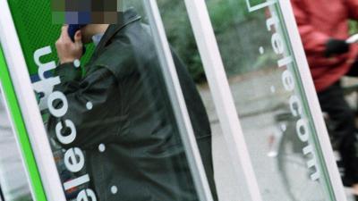 Man met handen omhoog uit telefooncel gepraat