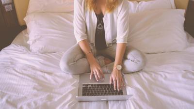 Vrouw op bed achter laptop